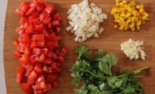 нарезав помидор кубиками и измельчив чеснок, лук, перец и кинзу.