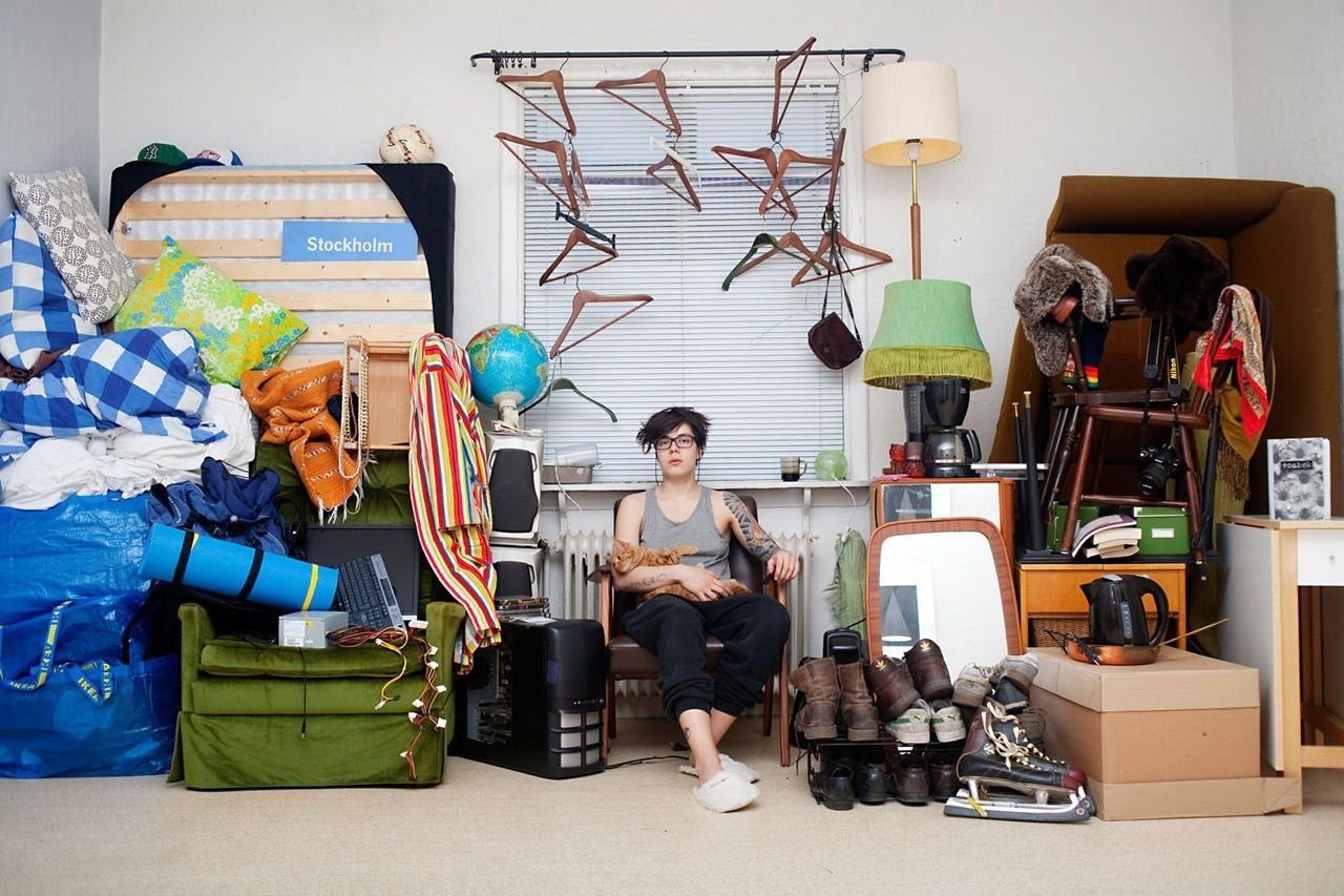 Нужно выбрасывать старые вещи. Девушка в гардеробной. Много вещей. Разбросанные вещи. Ненужные вещи.