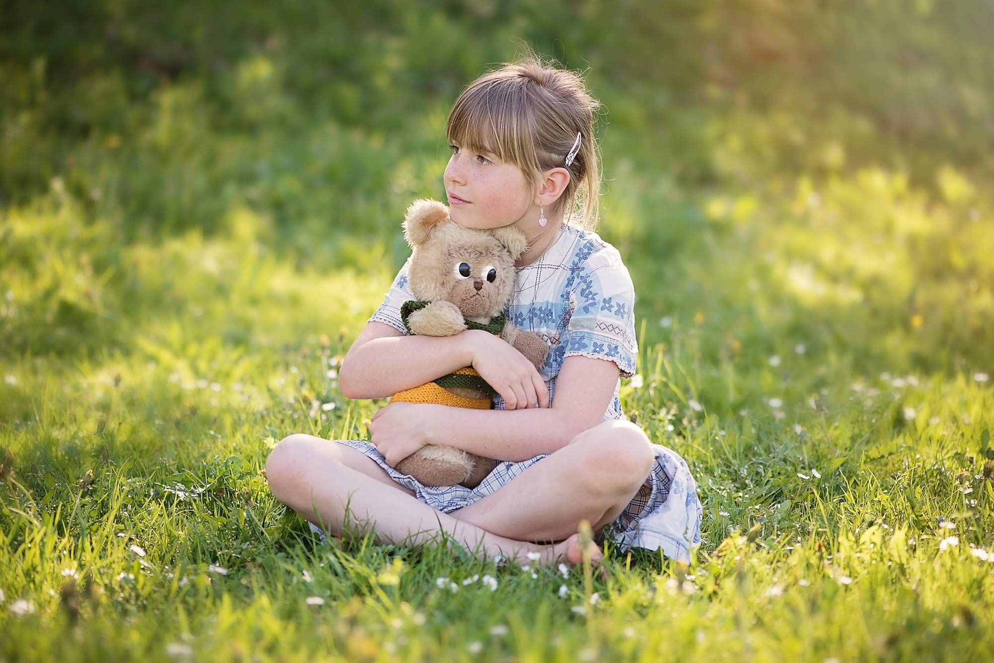 Дети просторов. Ребенок обнимает игрушку. Девочка сидит на траве. Фотосессия на природе. Маленькая девочка с игрушкой.
