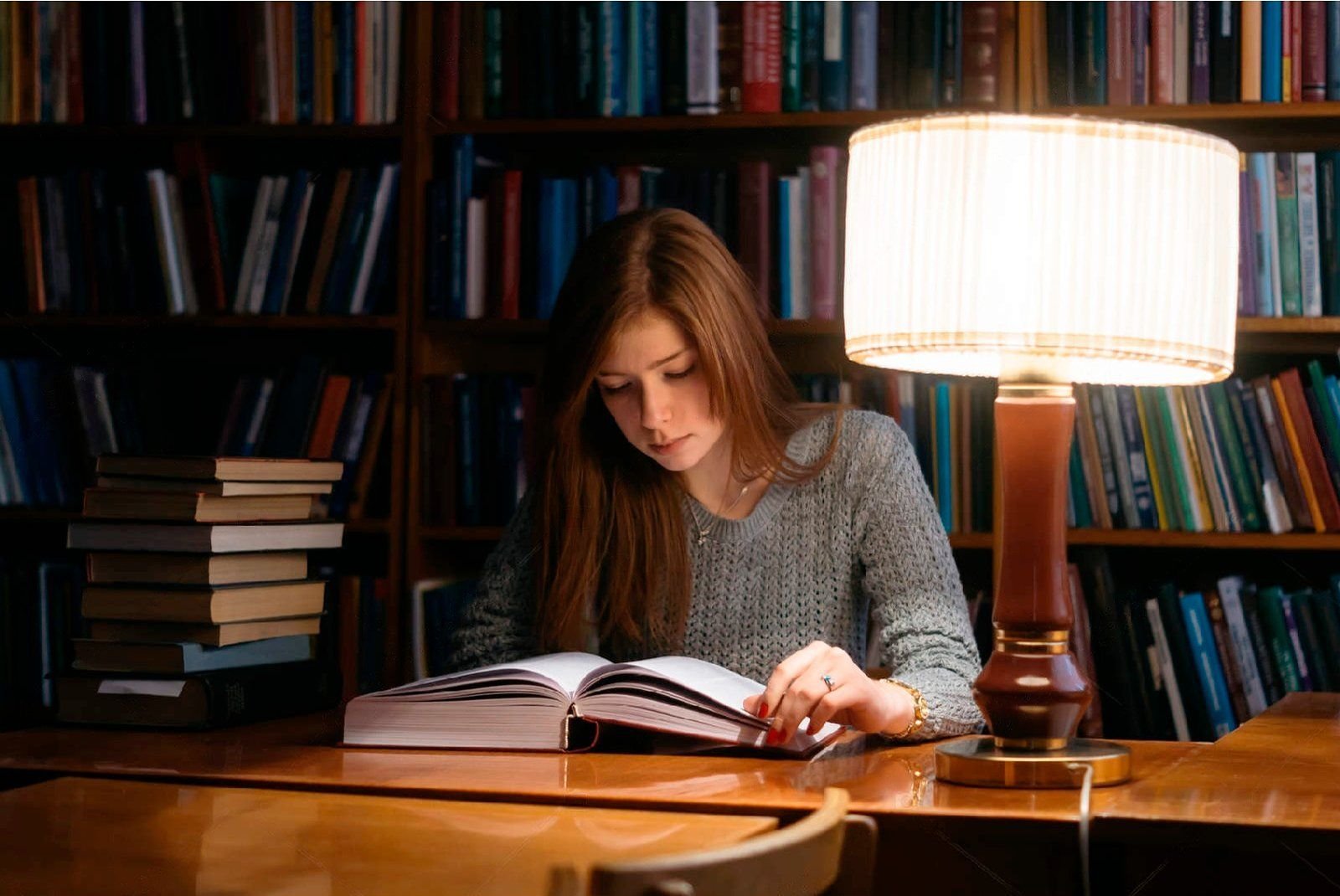 She reads in the evening. Девушка в библиотеке. Девушка сидит в библиотеке. Стол в библиотеке. Девушка читает за столом.