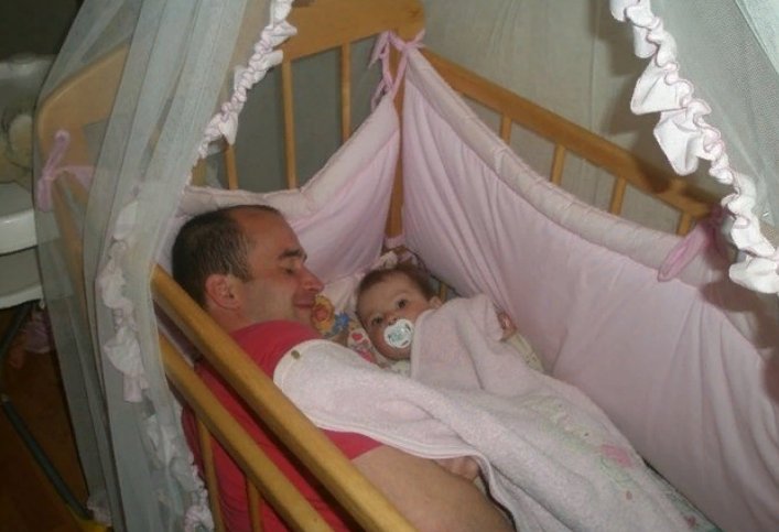 Отец усыпляет дочь. Папа уснул в детской кроватке. Ребенок в детской кроватке. Отец уснул в детской кроватке. Колыбель для детей.