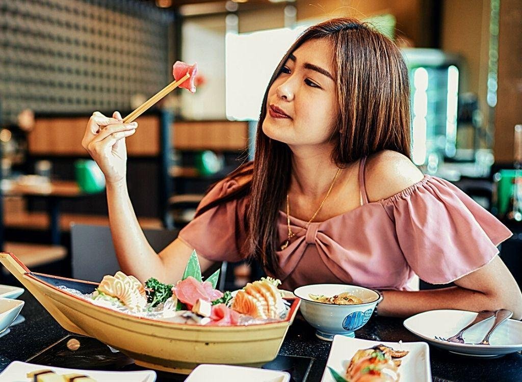 Девушка есть суши. Японский стол с едой. Еда на японке. Азиатка с едой. Китаянка с едой.