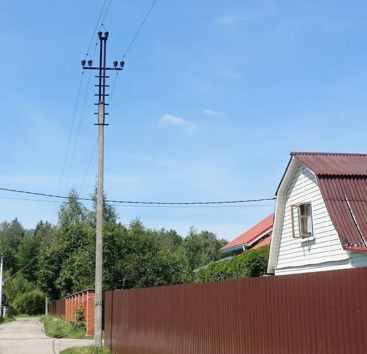 невысокий забор. электрический столб рядом с забором. столб линии электропередач на участке. столб рядом с домом. подвод электричества к дому.