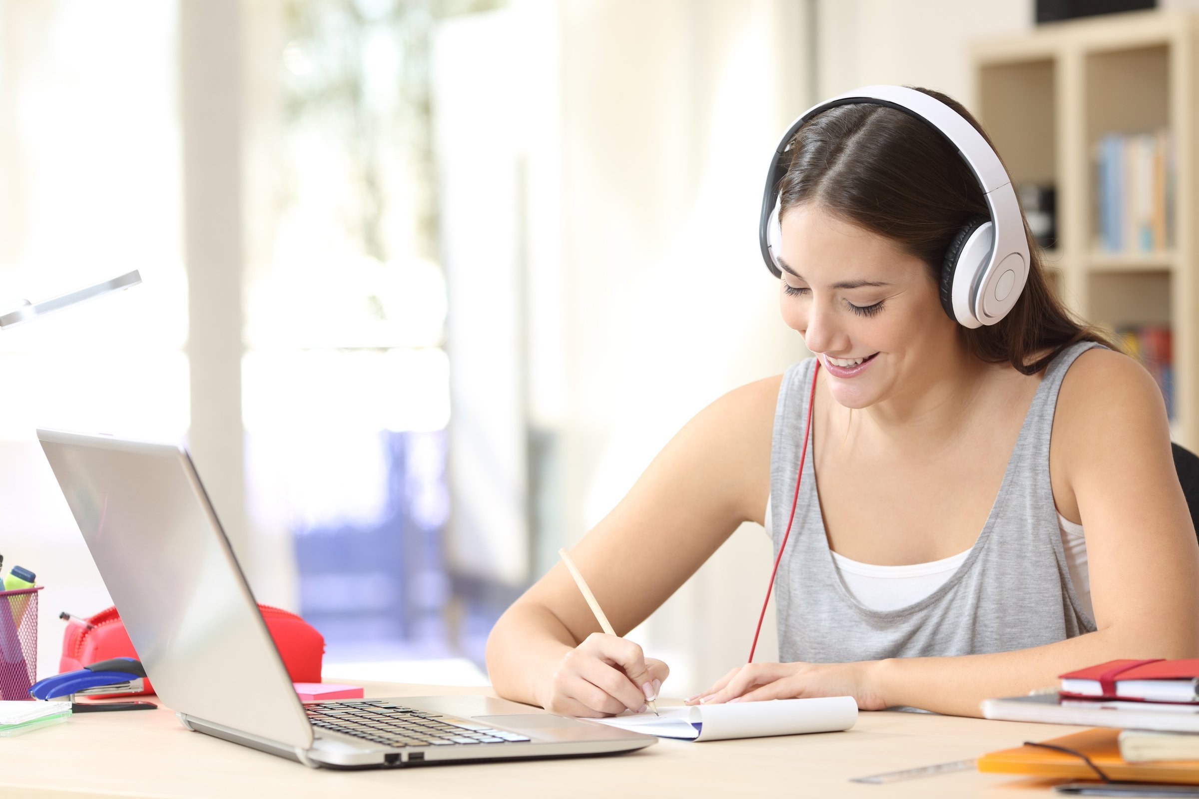 Аудио обучение языков. Девушка с ноутбуком и наушниками. Репетиторство по скайпу. Девушка учит английский.