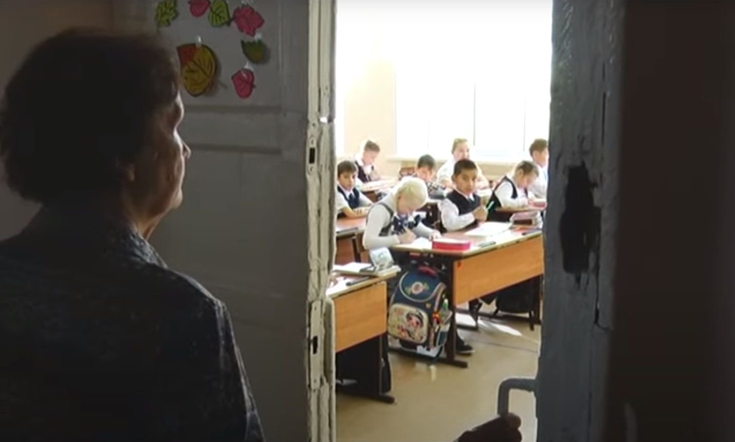 учительница сидит на парте