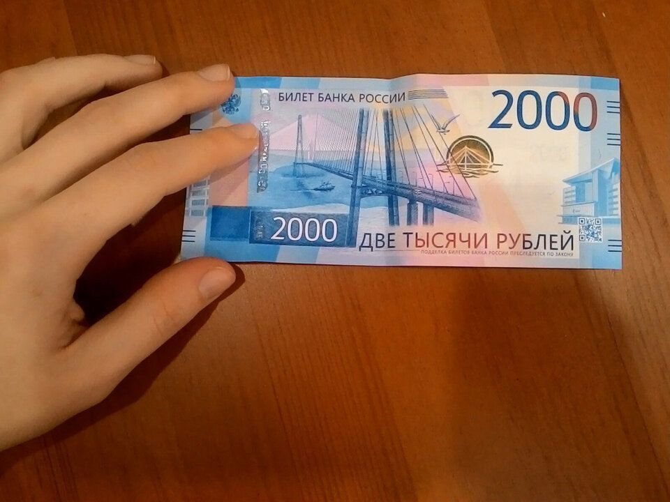 2 т р. 2000 Рублей. 2 Тысячи в руках. Две тысячи рублей. Купюра 2000 рублей на столе.