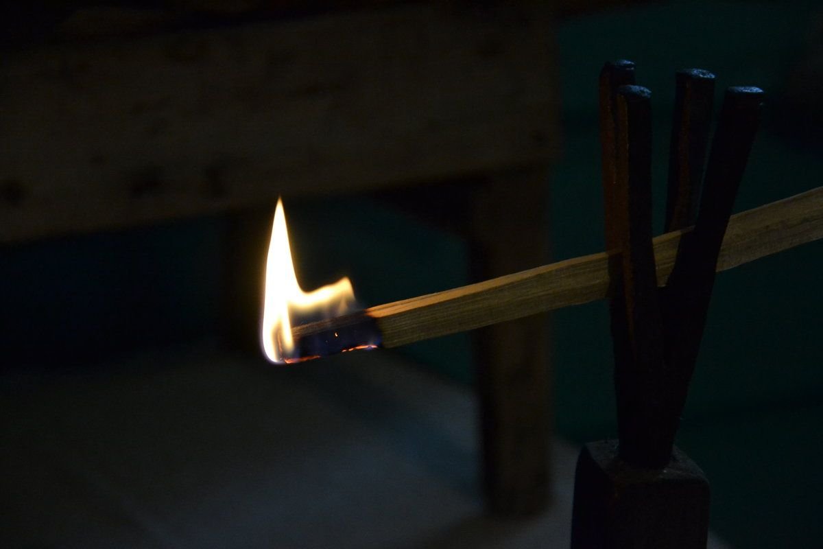 зажигалка с огнем. горящая спичка на черном фоне. рука со спичкой. темно зажечь. свеча на столе в темноте.