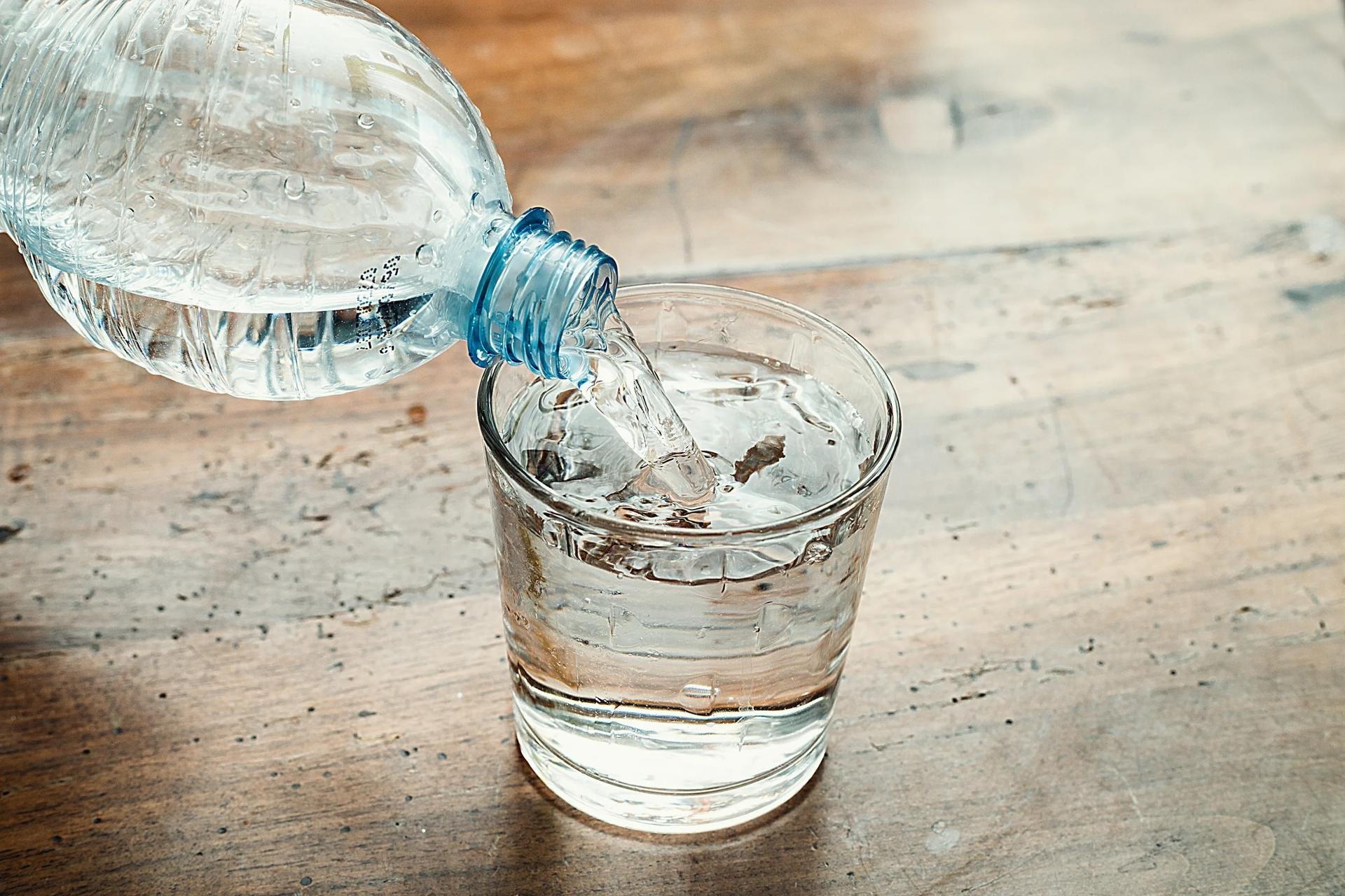 В бутылки стекает вода. Стакан воды. Бутылка для воды. Бутылка воды и стакан. Вода из бутылки.