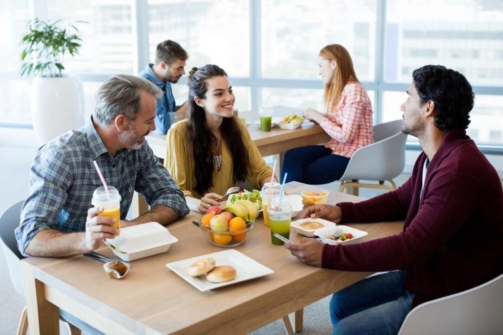 Есть ли обеденный перерыв. Беседа за столом. Люди обедают в офисе. Завтрак с коллегами. Сотрудники обедают в кафе.