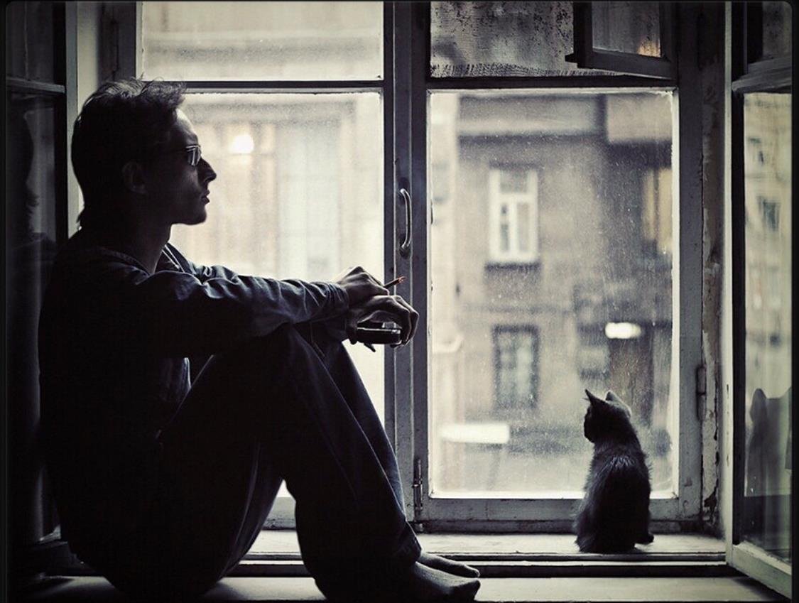 Терпеливо выжидая. Парень у окна. Одинокий мужчина у окна. Сидит у окна. Одинокий человек у окна.