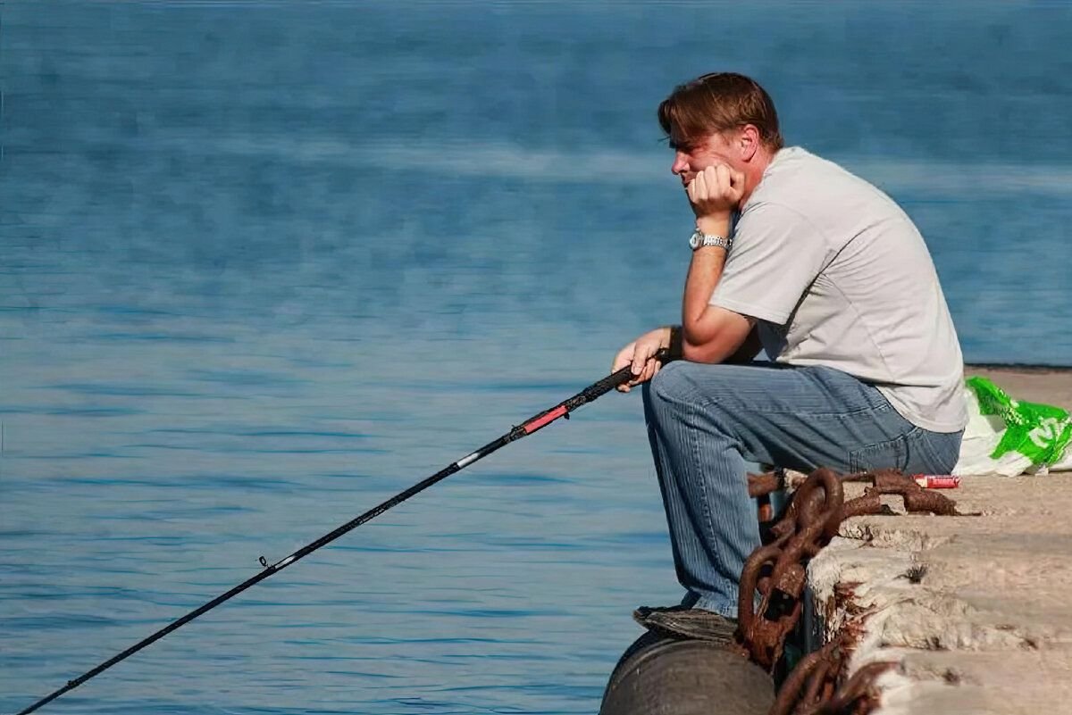 Клев на море. Грустный Рыбак. Рыбак сидит. Человек рыбачит на берегу. Мужик с удочкой.